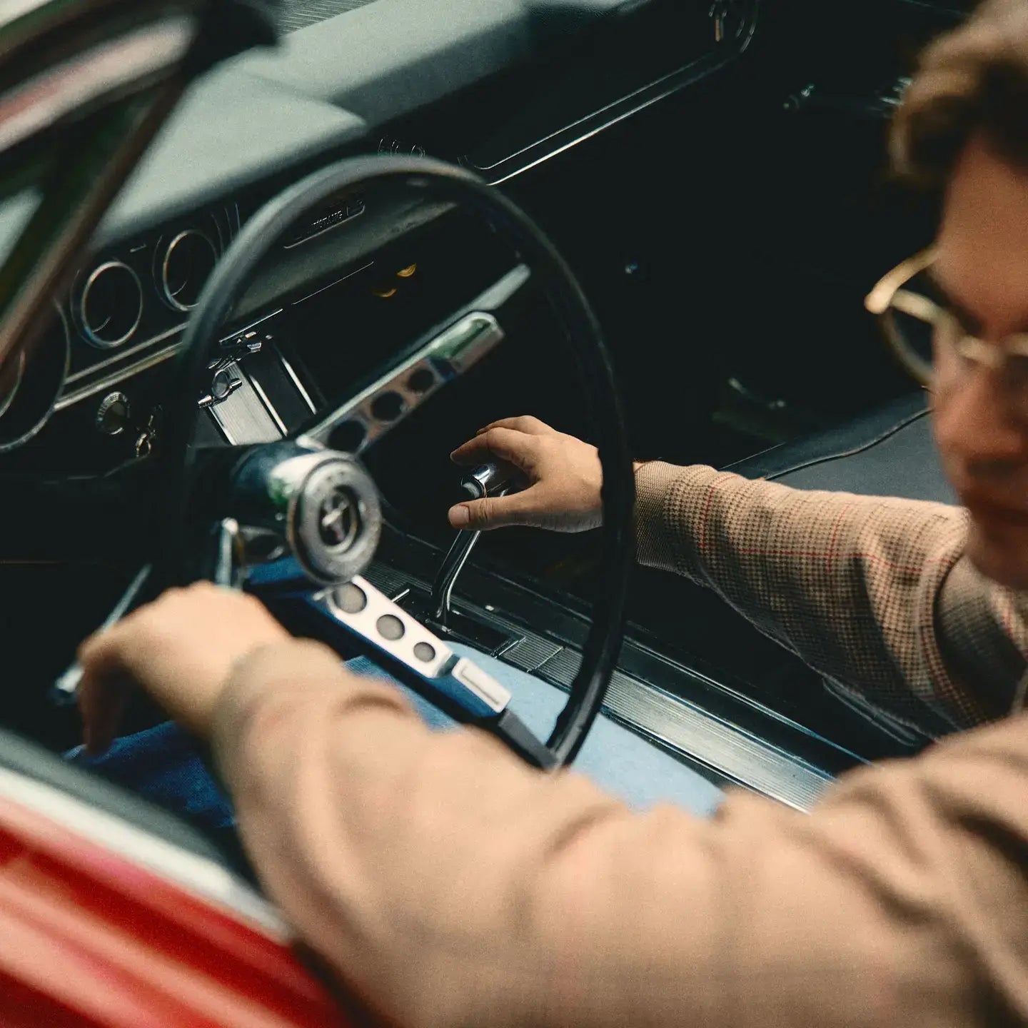 close up of car steering wheel with man holding the shift