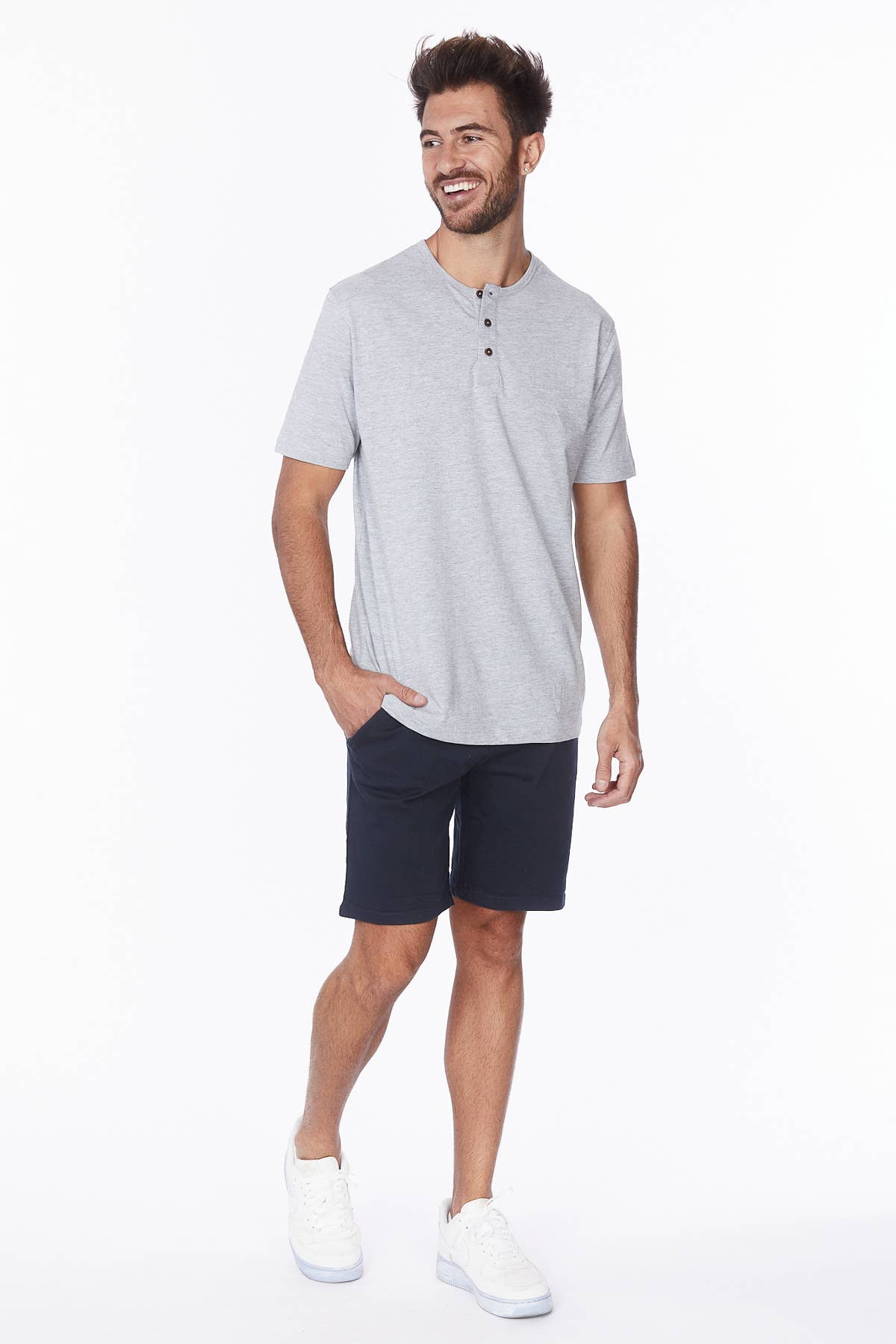 Male model wearing navy shorts with a grey tee and white sneakers.