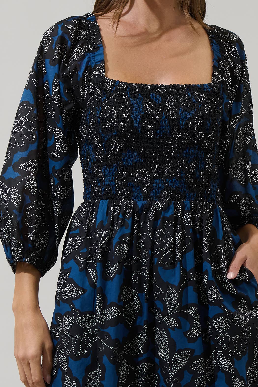 Woman wearing a blue and black patterned dress with a plain background