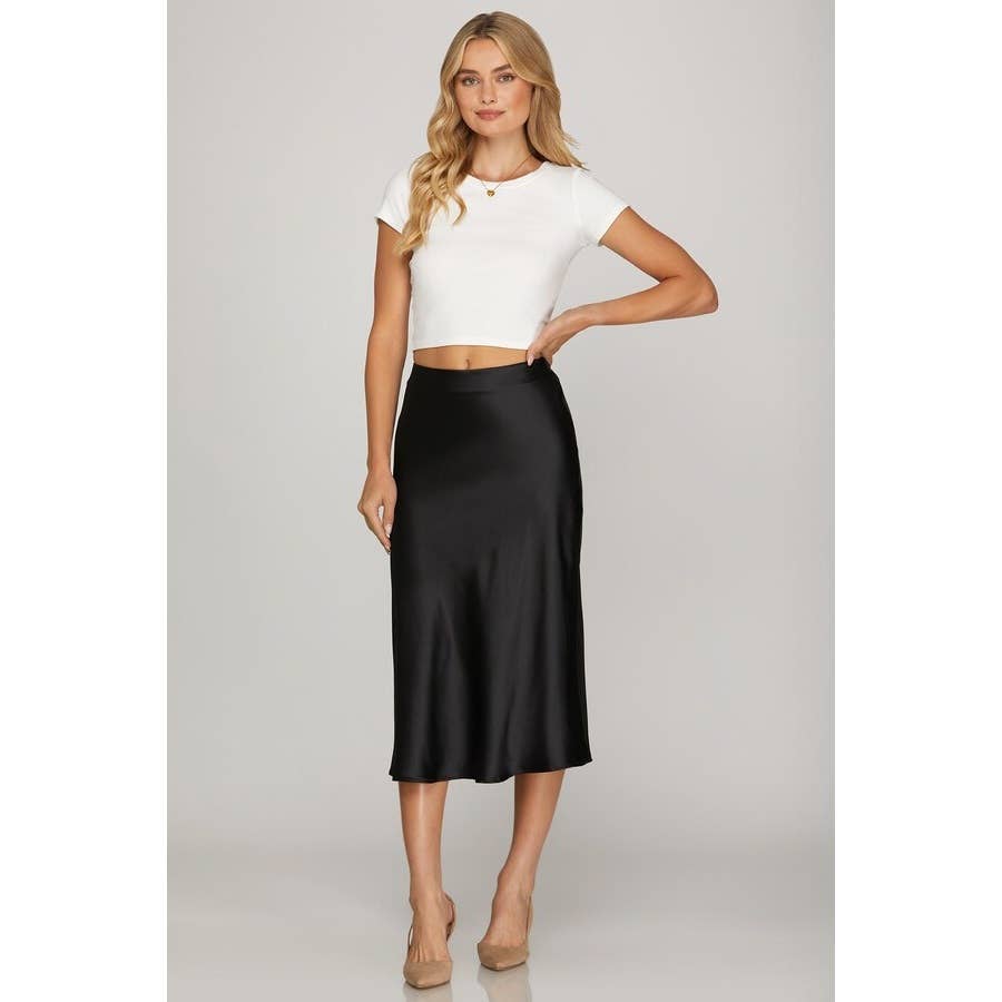 Woman wearing a white top and black skirt on a plain background