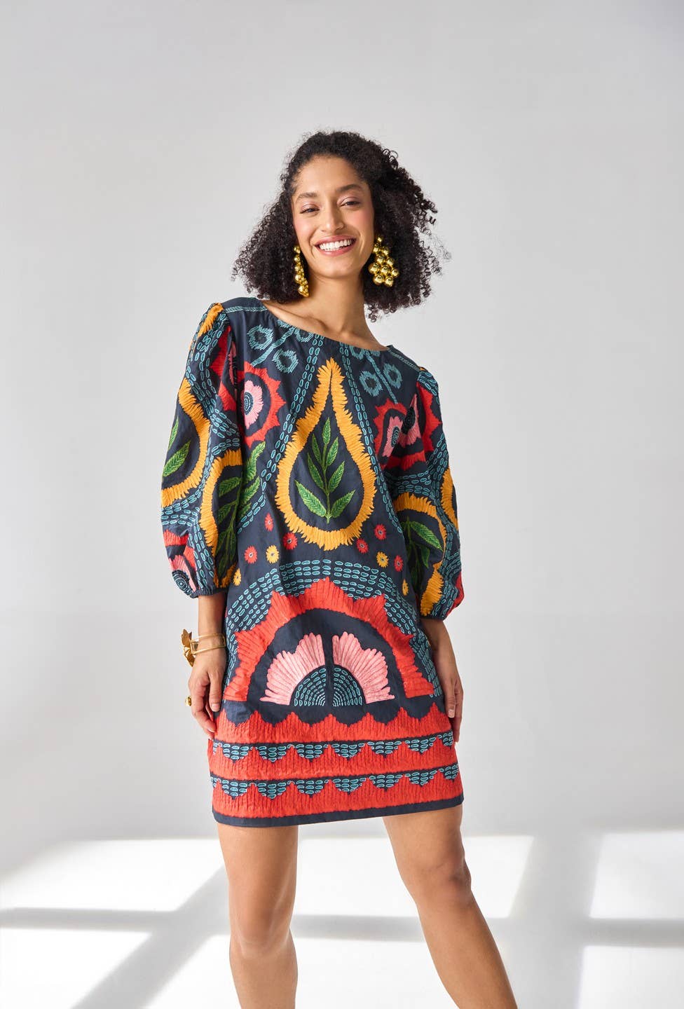 Woman wearing a colorful patterned dress against a white background