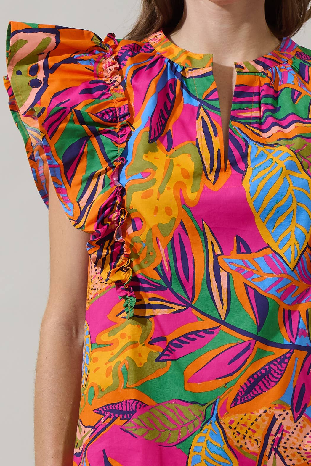 model in a multi color tropical print blouse with a white pant