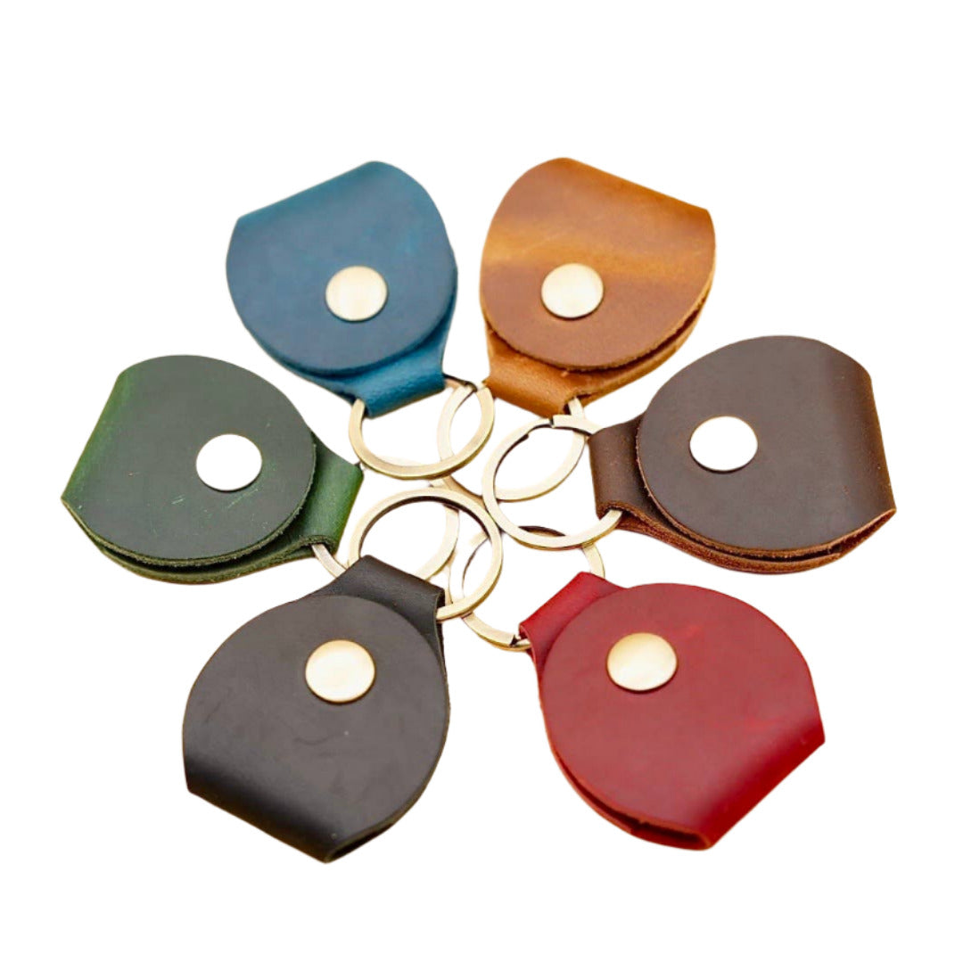six leather guitar pick holder keychain in blue, green, black, red, dark brown and light brown.