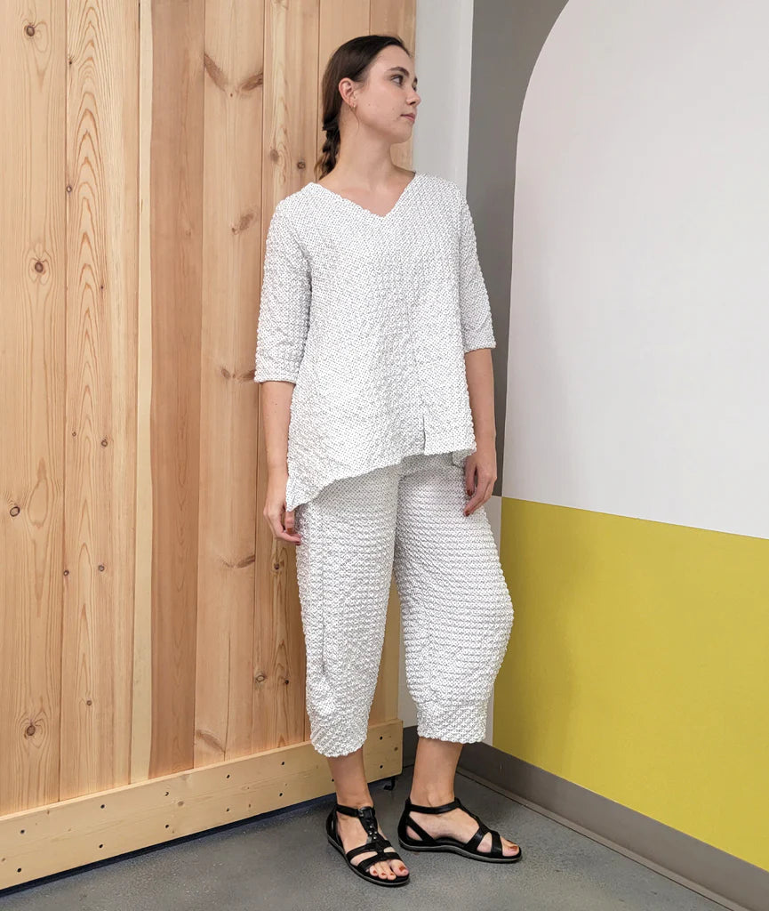 model wearing white with black dot v-neck flowy top with matching pants