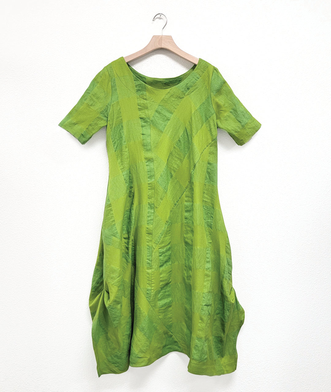 large check lime green dress with an asymmetrical body, round neckline, elbow length sleeves, and contrasting panels across the body