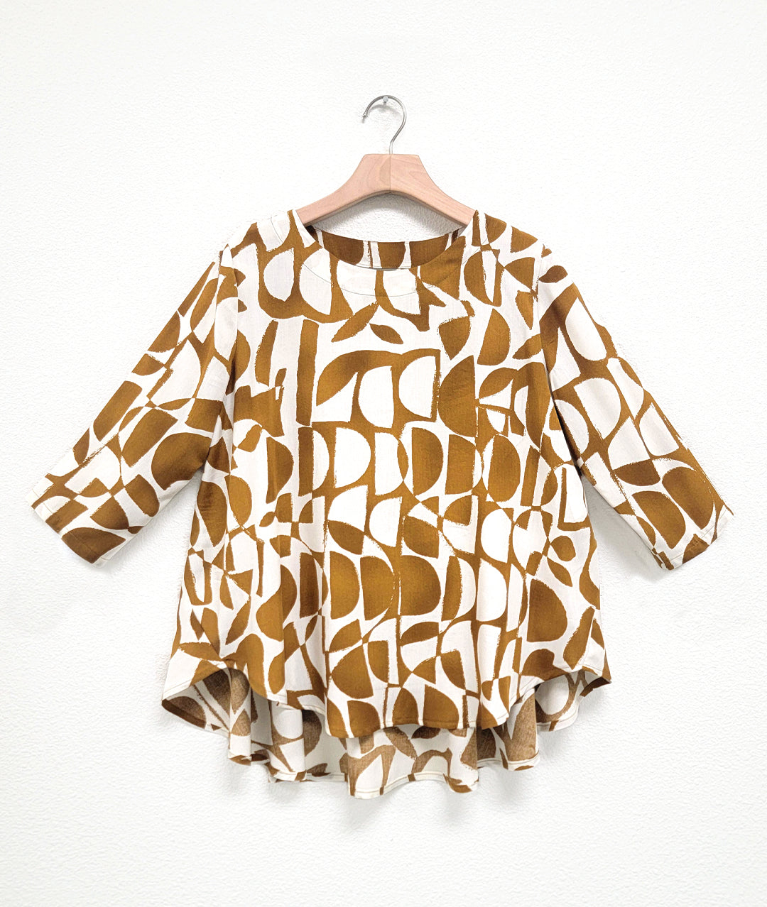 white and brown mod print pull over top with a high-low hem, 3/4 sleeves and a full bodied back