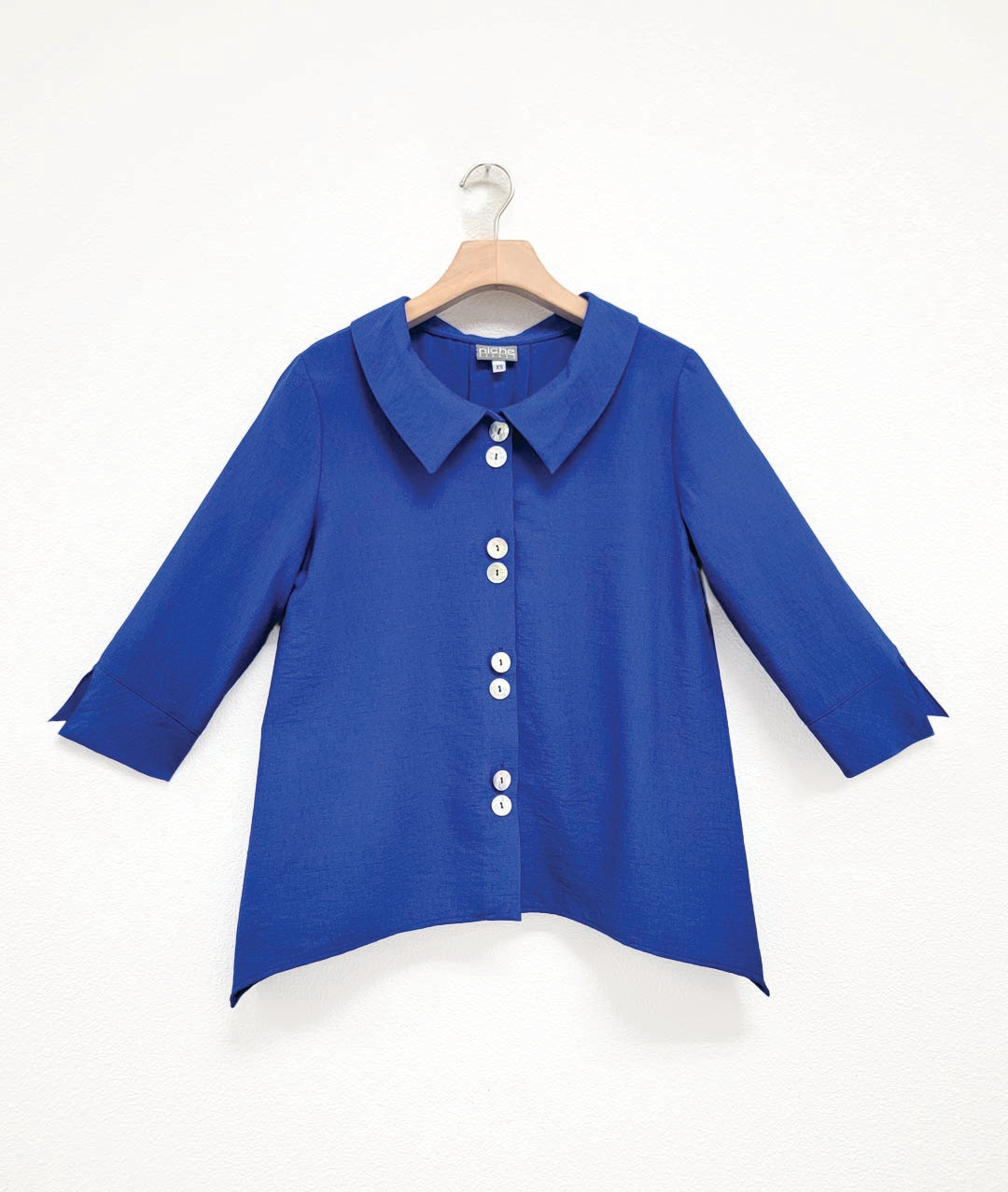 cobalt blue button down blouse with 3/4 sleeves, twin button sets, and a hem with dips on either side