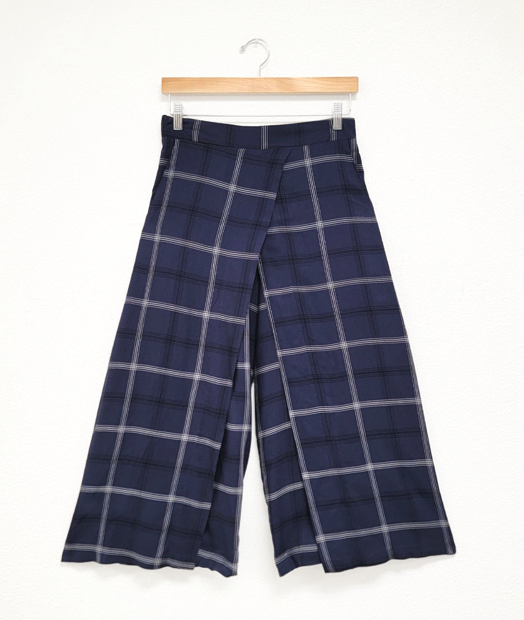 wide leg navy pant with an overlapping panel in the front on either leg. plant is navy blue with a black and white plaid stripe