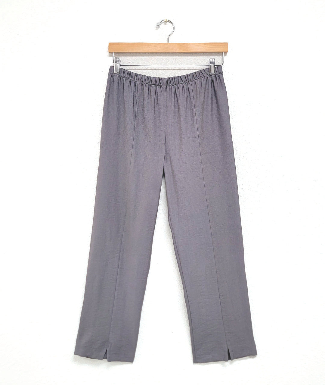 grey straight cut pants with an elastic waistband and small slits at the ankle