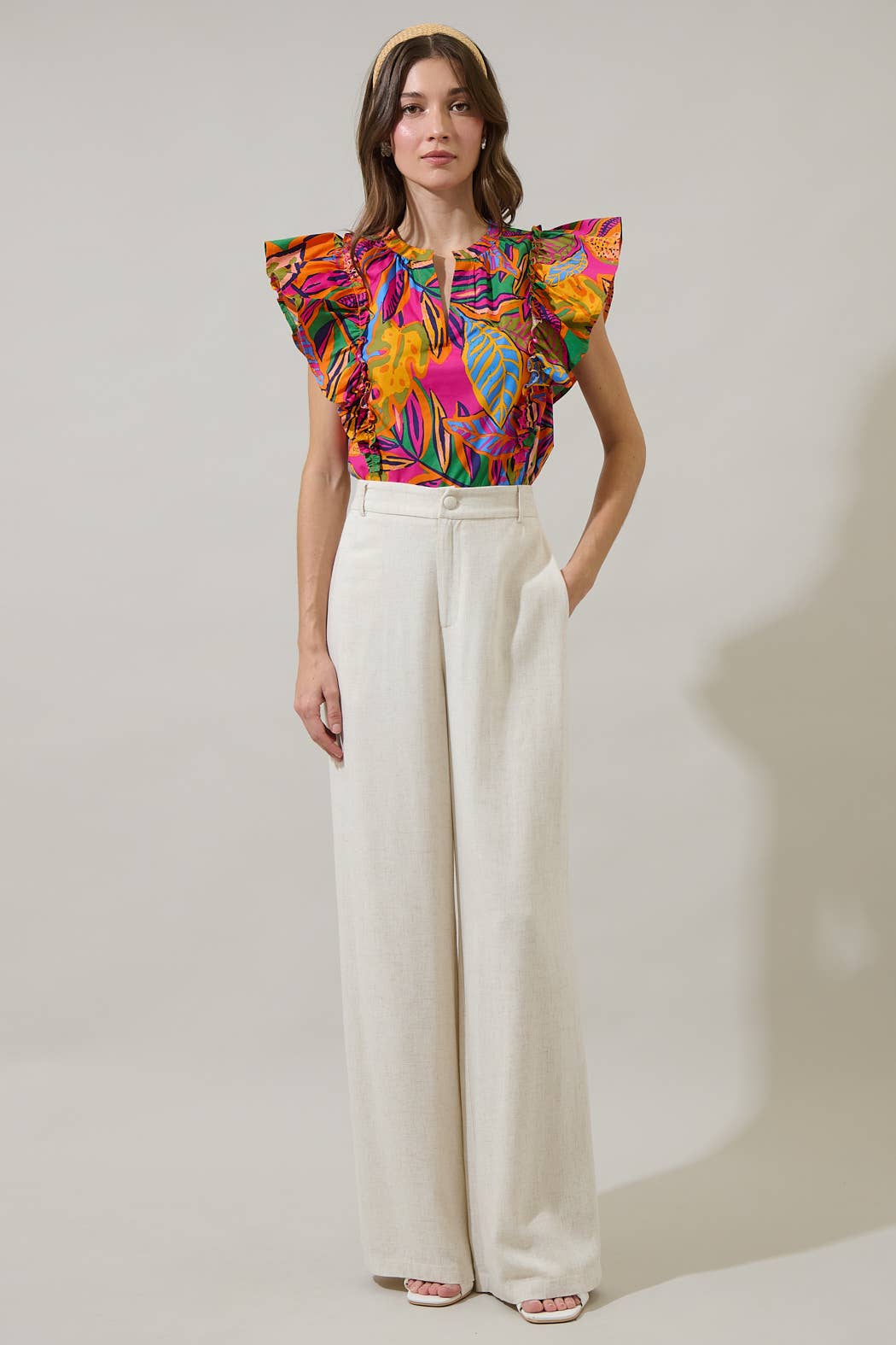 model in a multi color tropical print blouse with a white pant