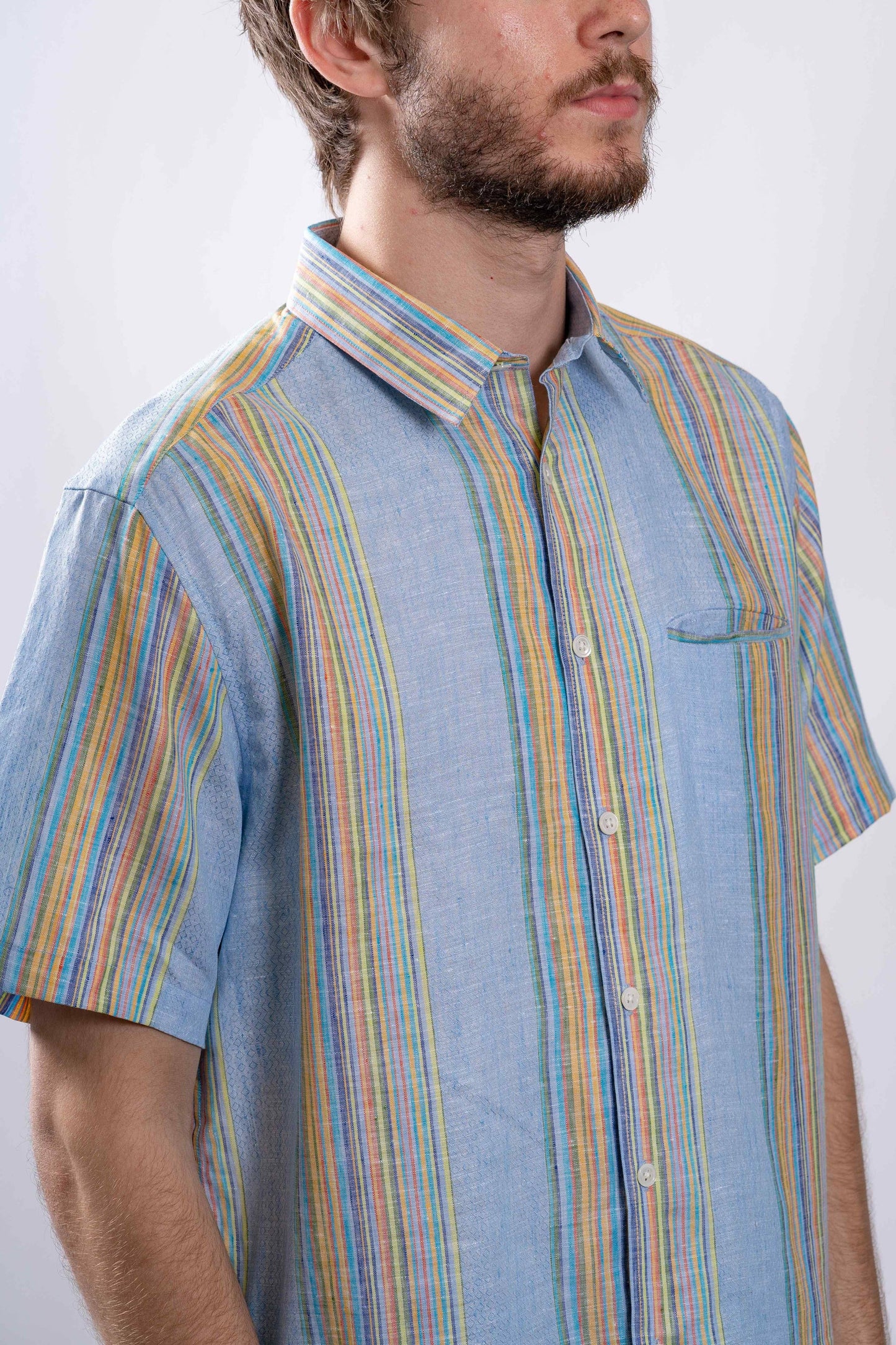 model wearing blue and colorful striped linen button up collared short sleeve shirt