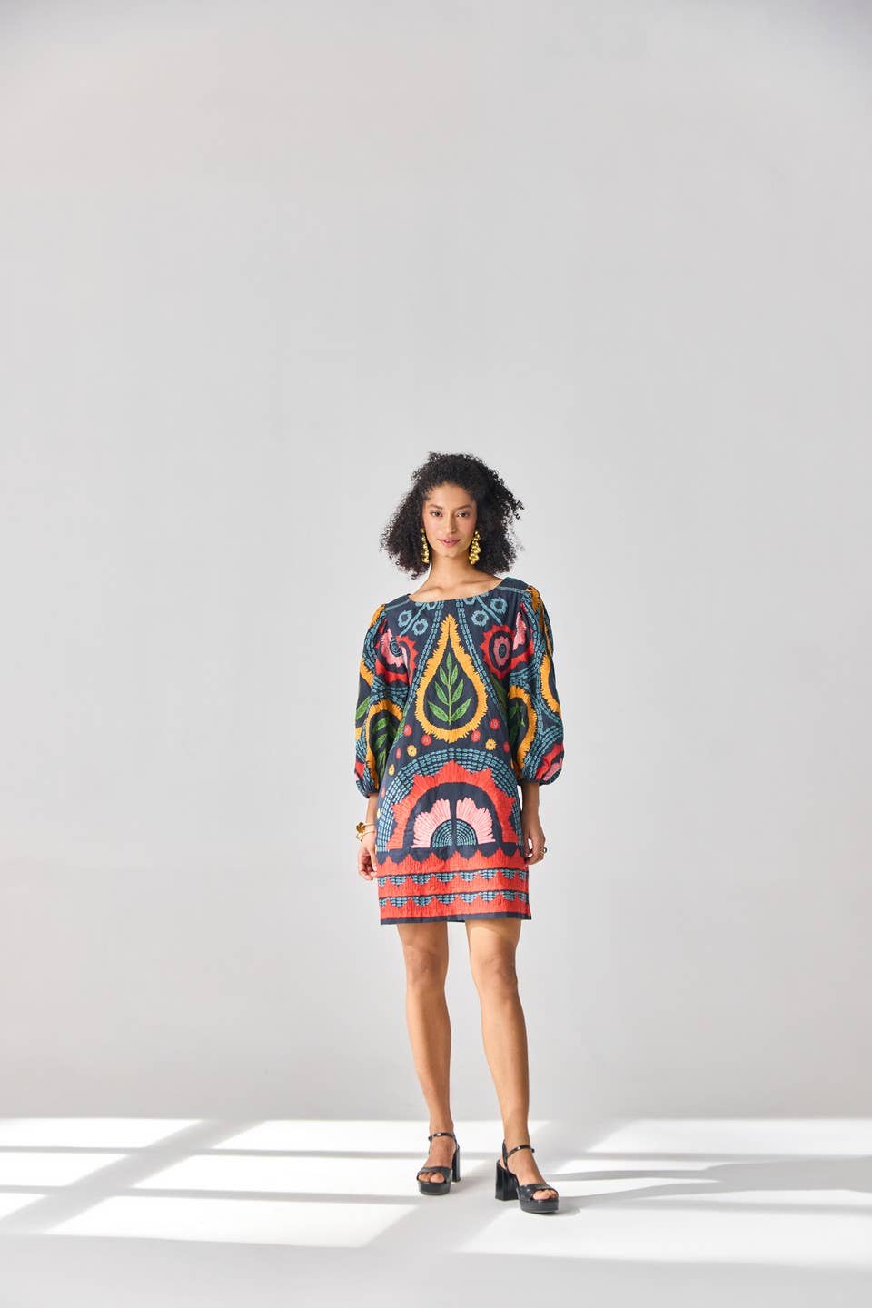 Woman wearing a colorful patterned dress on a white background