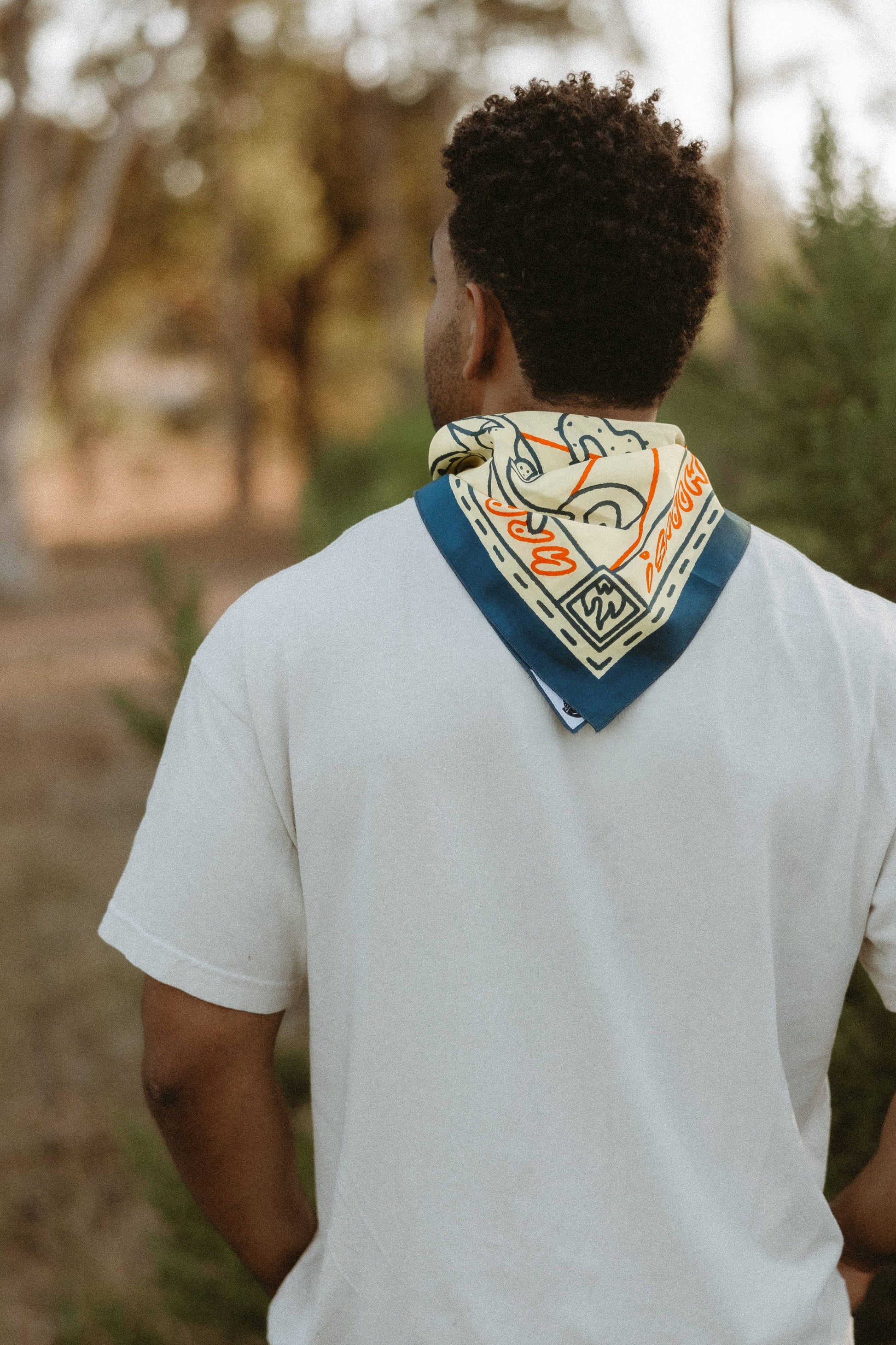 man turned around wearing bandana around neck and white shirt