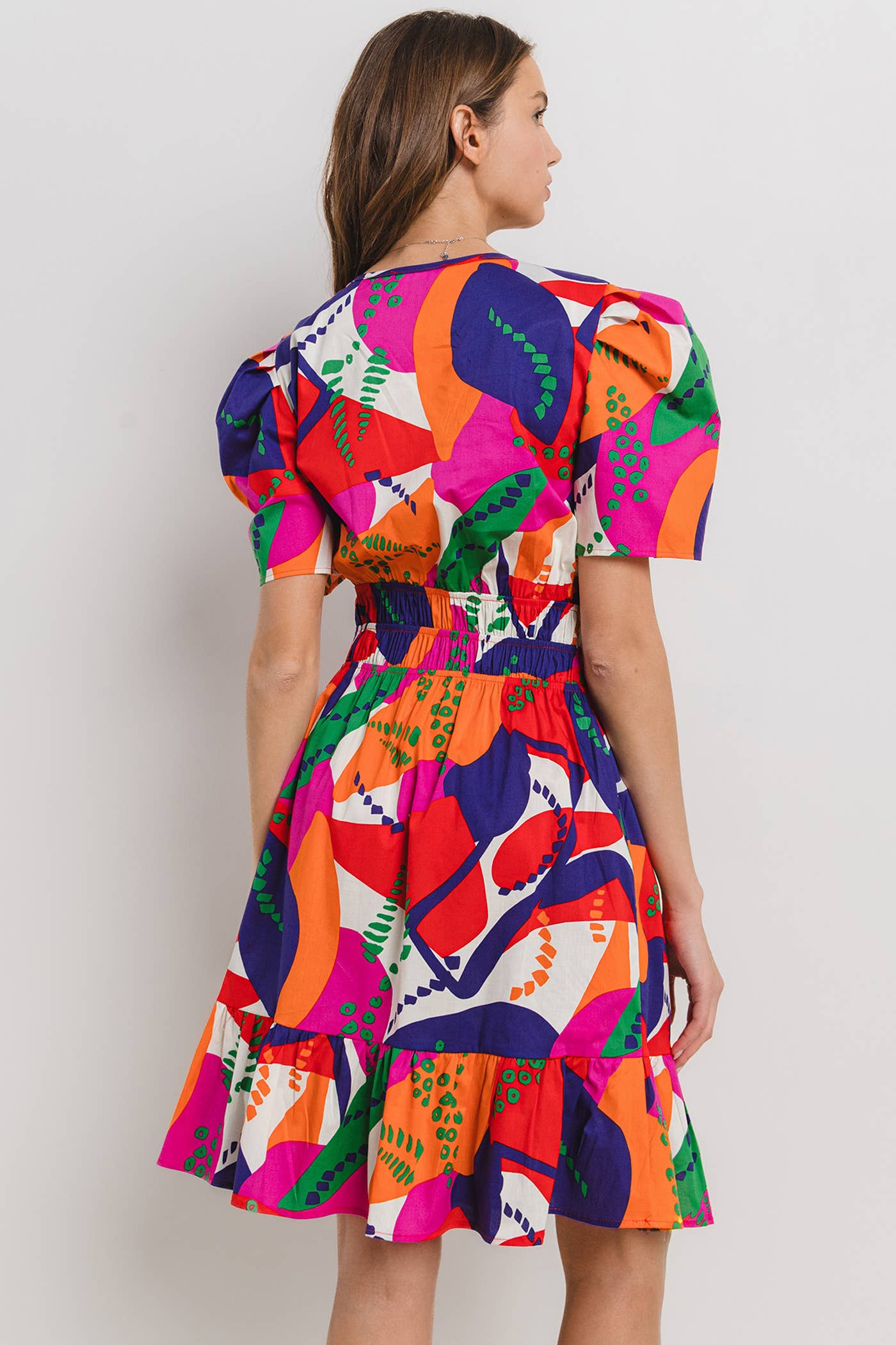 back view of model wearing a tropical printed dress with puffy sleeves