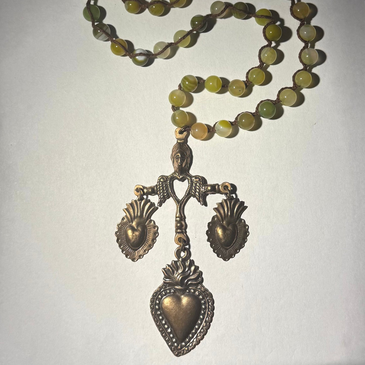 Necklace with green beads and bronze yalalag pendants on a plain background