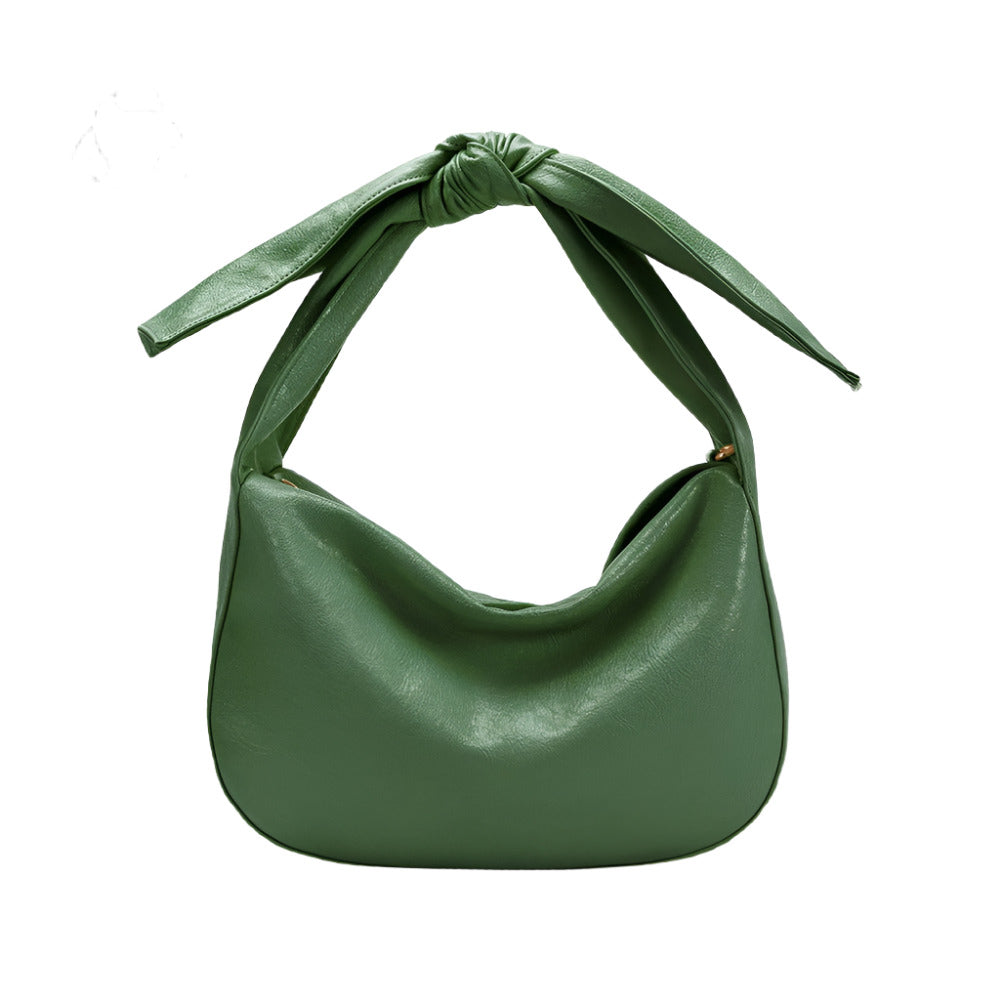 Green handbag with a bow strap detail on a white background