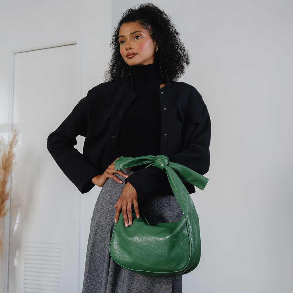 Woman holding a green handbag against a white background
