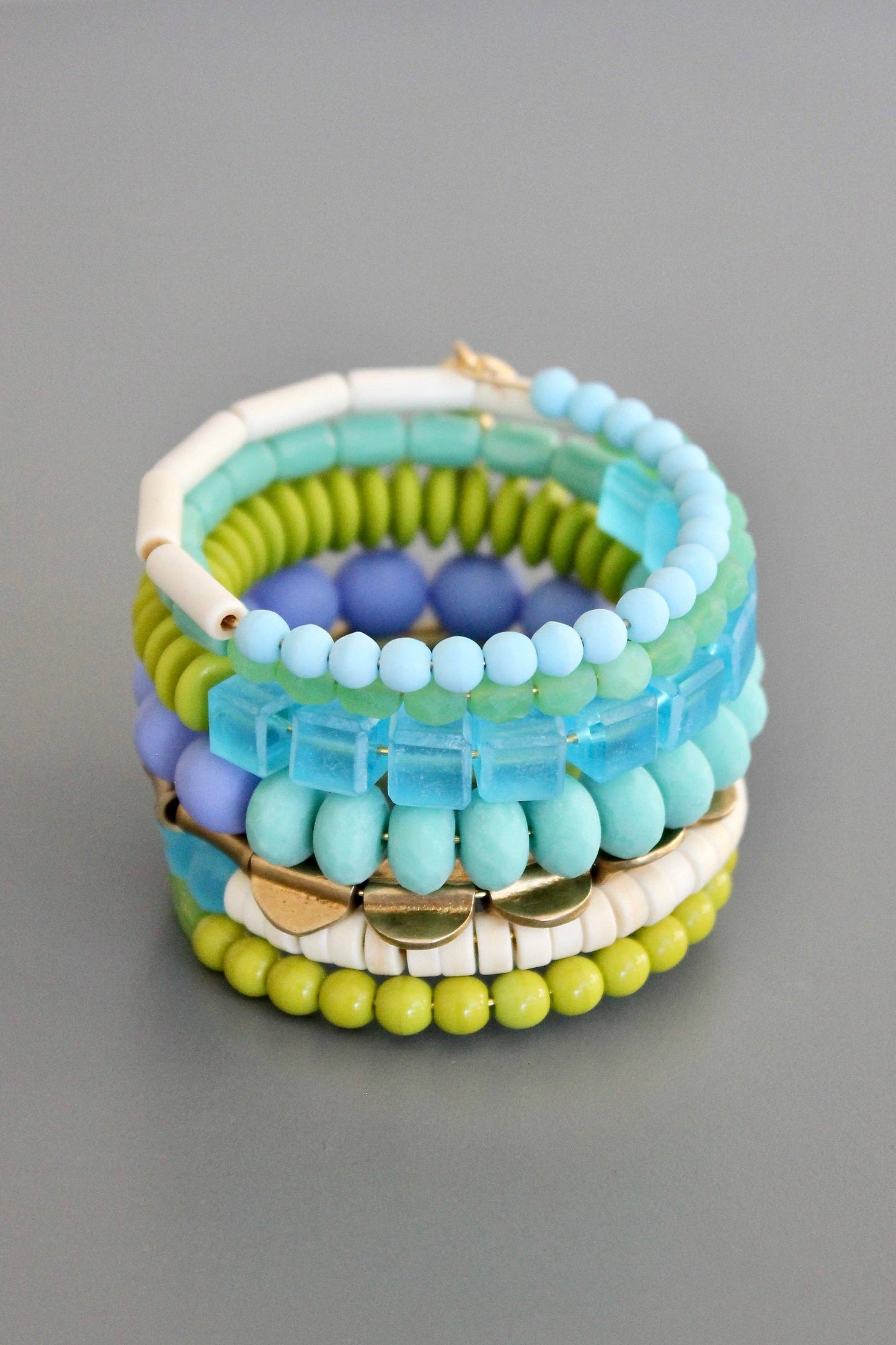 Stack of colorful beaded bracelets on a gray background