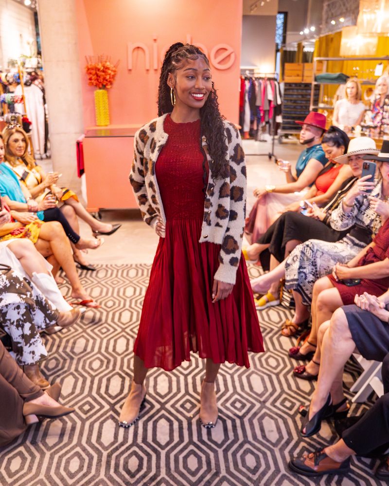 model in a red dress and leopard print cardigan walking down runway