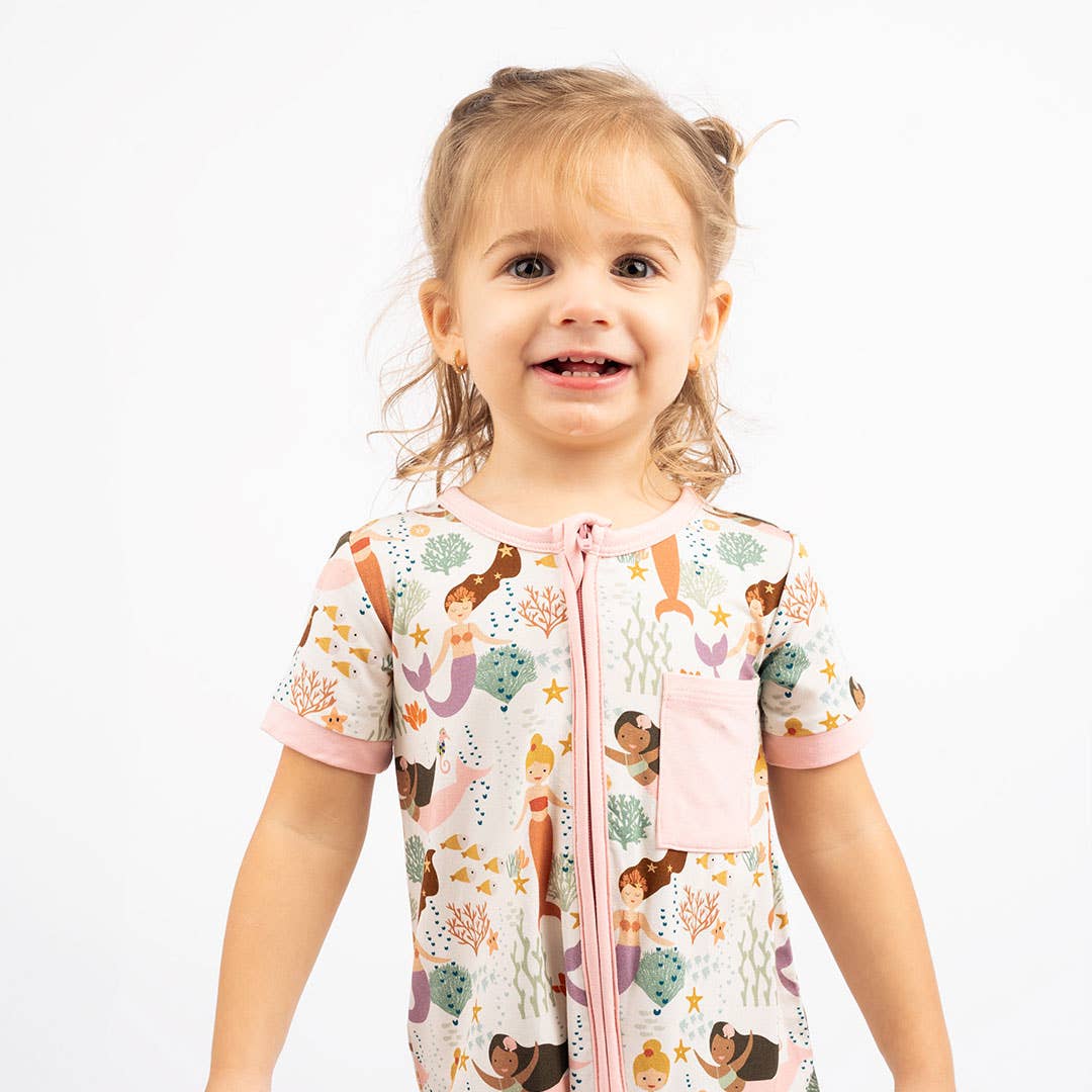 Child wearing a colorful pajama top with mermaid design on a white background