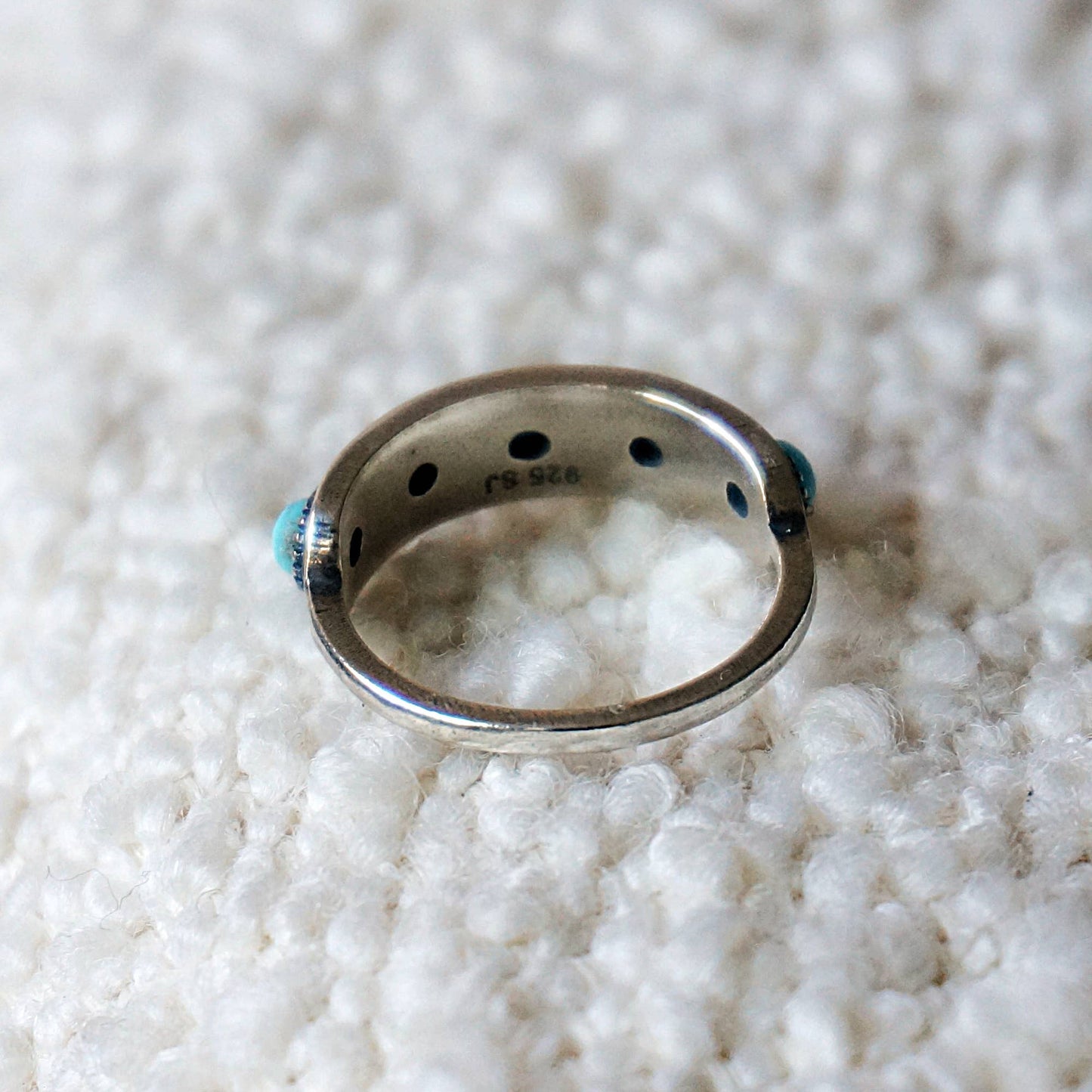 Silver ring with turquoise stones on a textured white surface