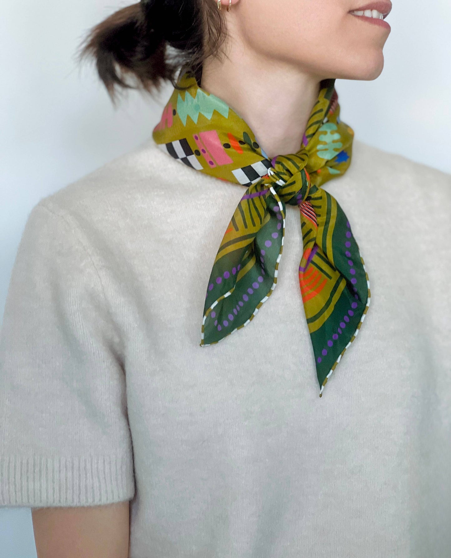 Person wearing a colorful patterned scarf on a plain background