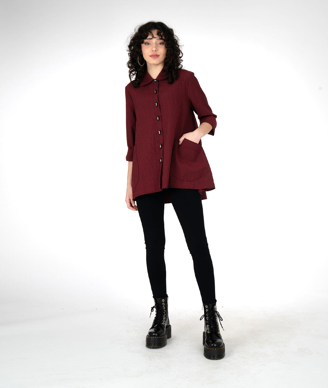 model in a long sleeve button down tunic length blouse, with oversized pockets and a high-low hem