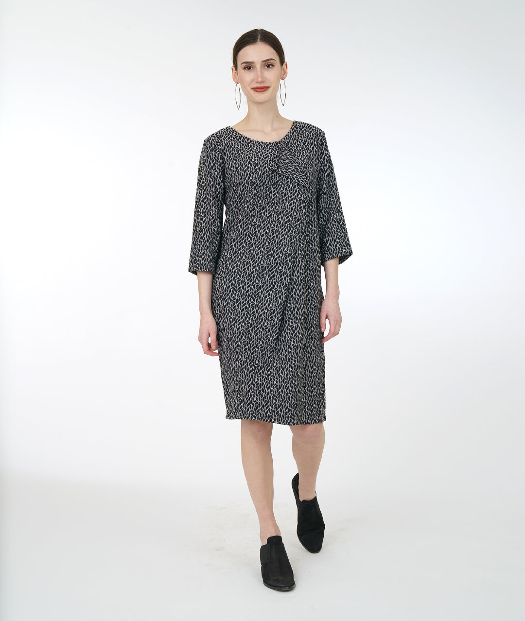 model in a black and grey leaf shift dress with a flounce down the front