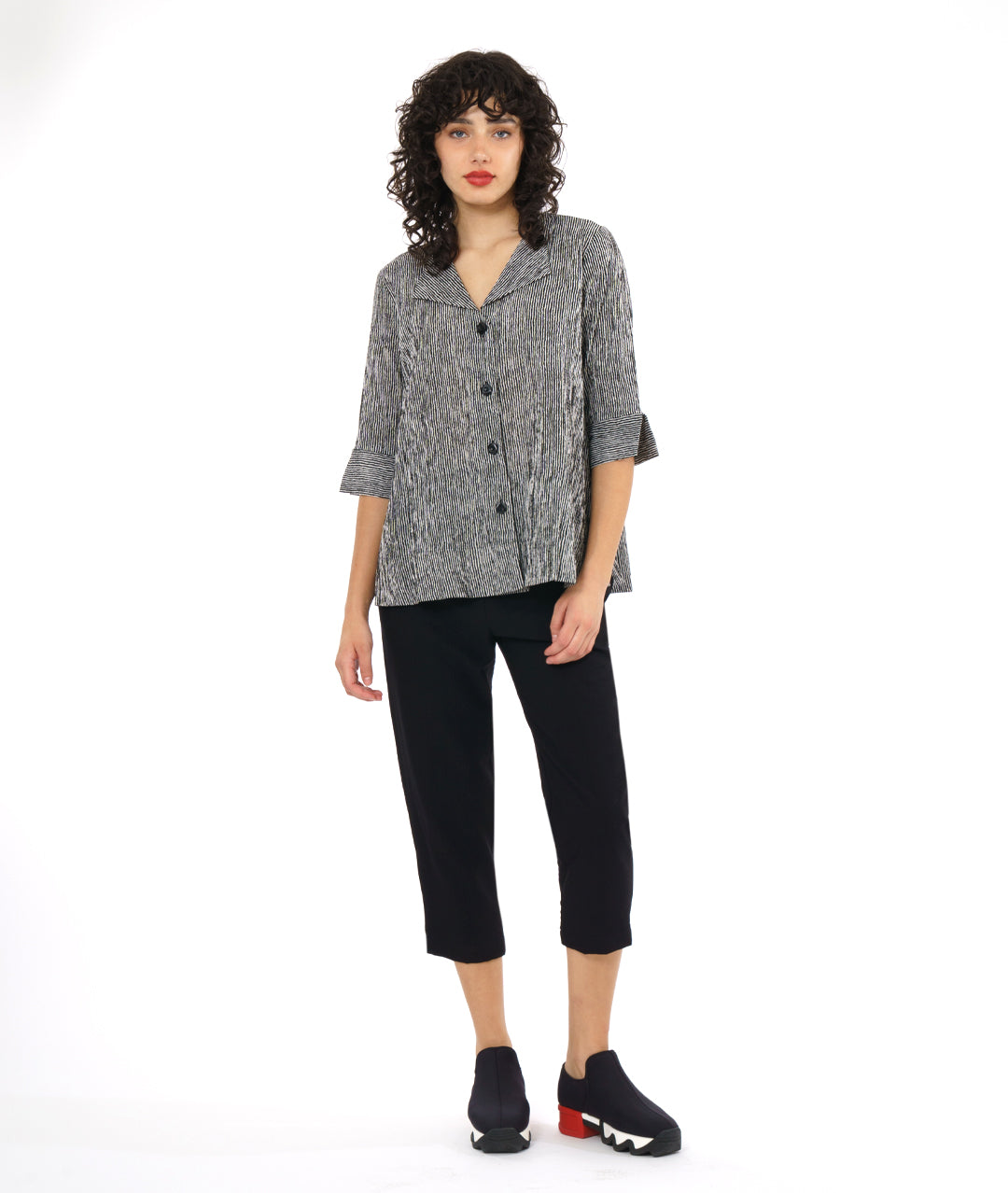 model in a slim black crop pant, with a black and white striped button down blouse. blouse has 3/4 sleeves and a flat collar