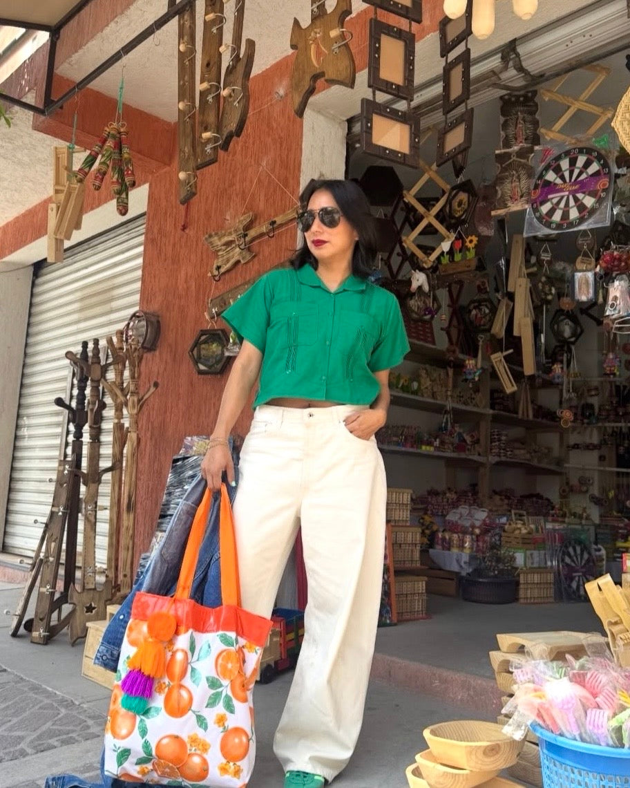 Woman wearing green shirt and white pants at a market