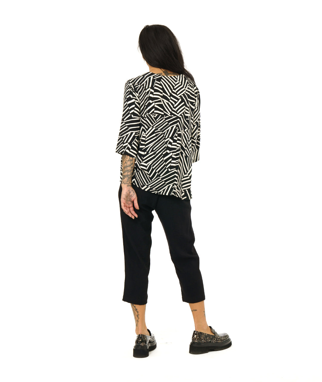 model in a black and white broken stripe print pullover top with 3/4 sleeves and a v-neck. worn with a simple black crop pant