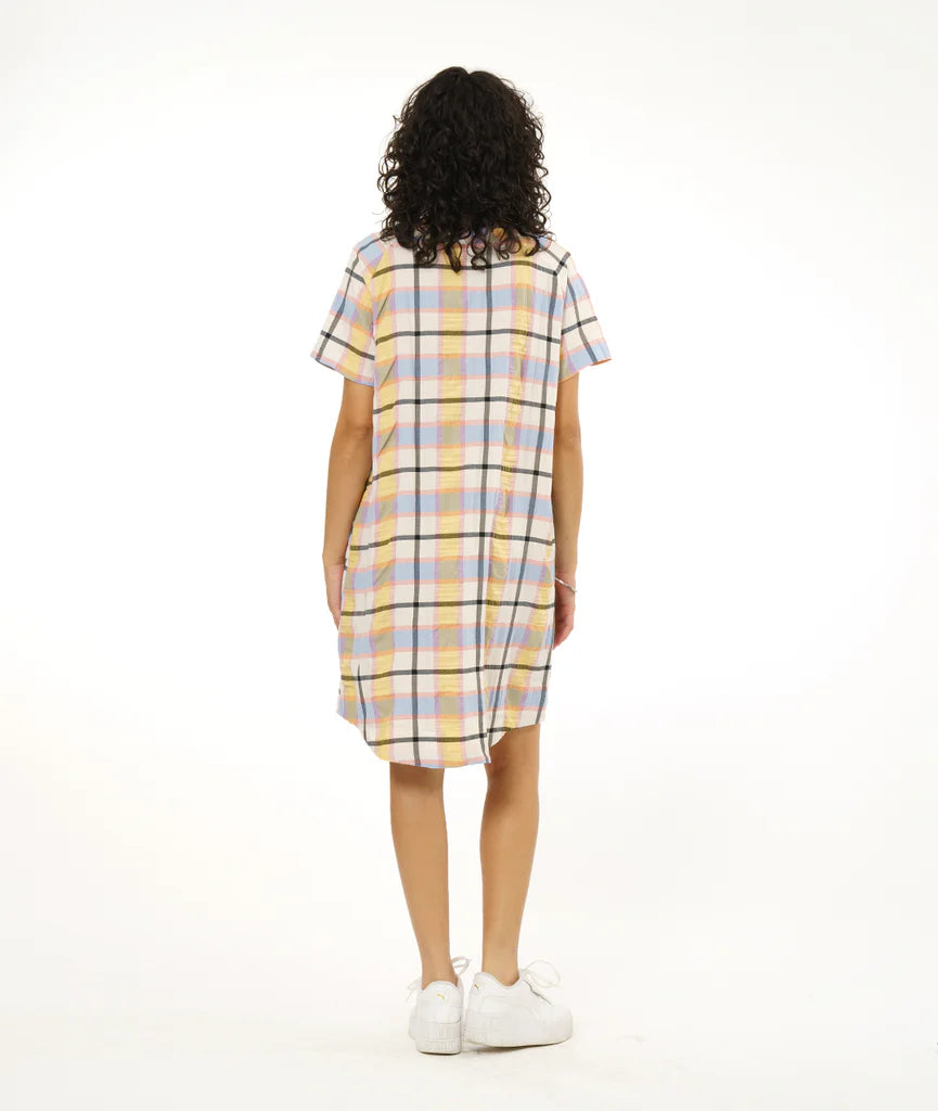 model showing back of round hem dress that hits below the knee with patch pockets, short sleeves and boat neck collar in a plaid pastel pattern paired with white sneakers
