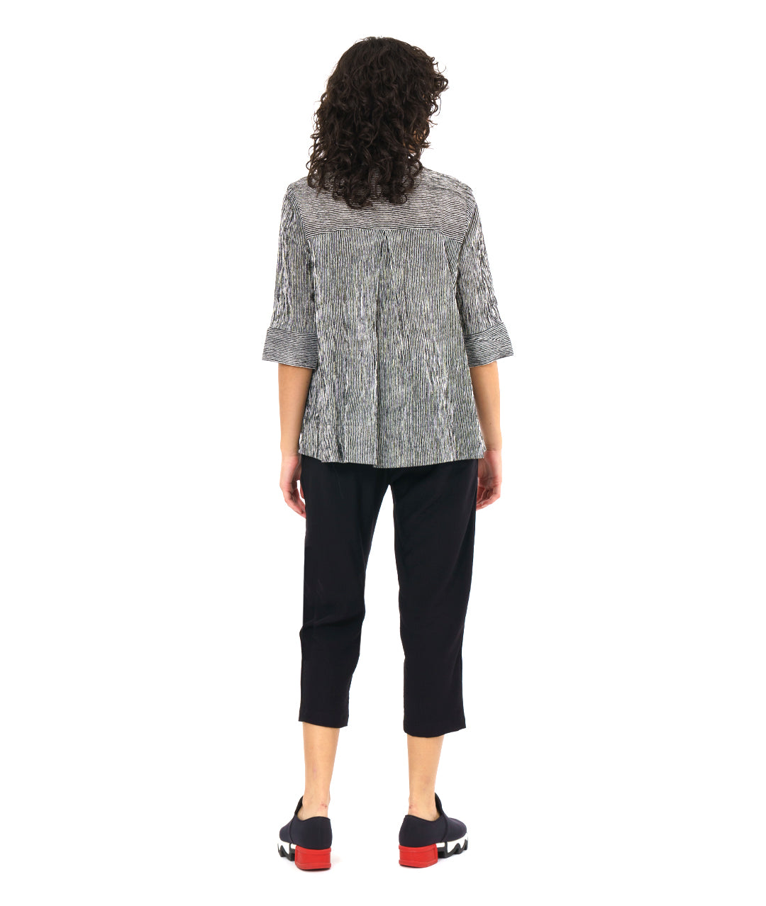 model in a slim black crop pant, with a black and white striped button down blouse. blouse has 3/4 sleeves and a flat collar