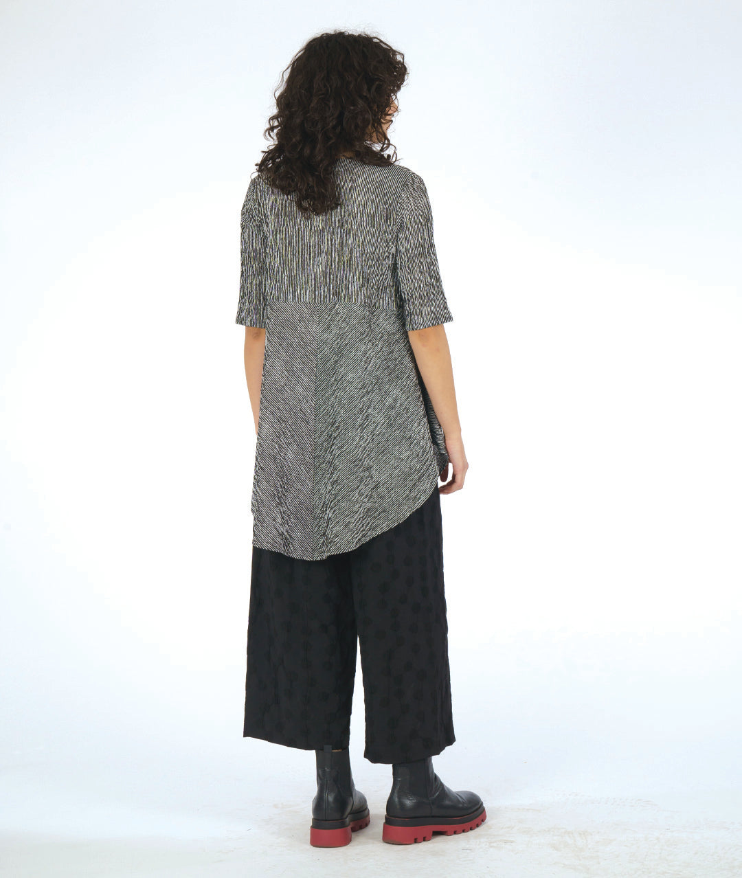 model in a wide leg black pant with a textured dot print. worn with a black and white striped blouse