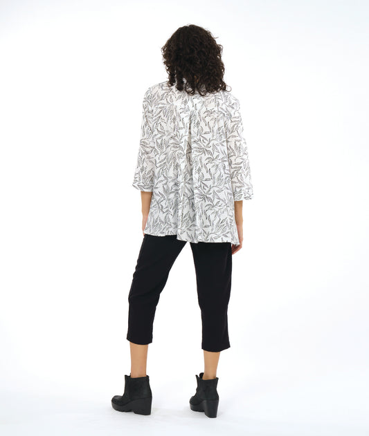 model in a slim black cropped pant, worn with a white button down blouse with a twinbutton detail, 3/4 sleeves, a long body and a floral print