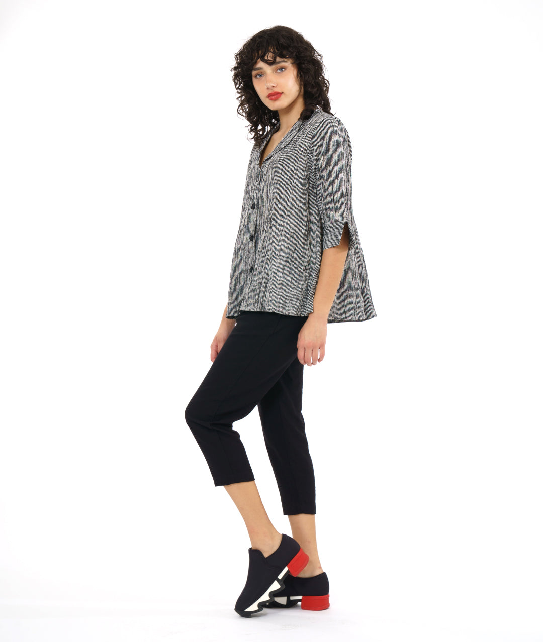 model in a slim black crop pant, with a black and white striped button down blouse. blouse has 3/4 sleeves and a flat collar
