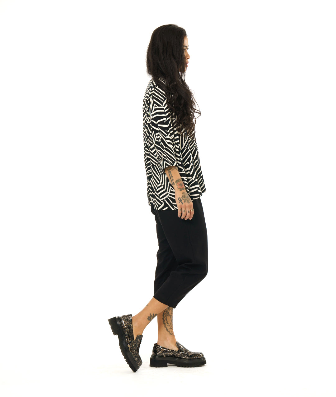 model in a black and white broken stripe print pullover top with 3/4 sleeves and a v-neck. worn with a simple black crop pant