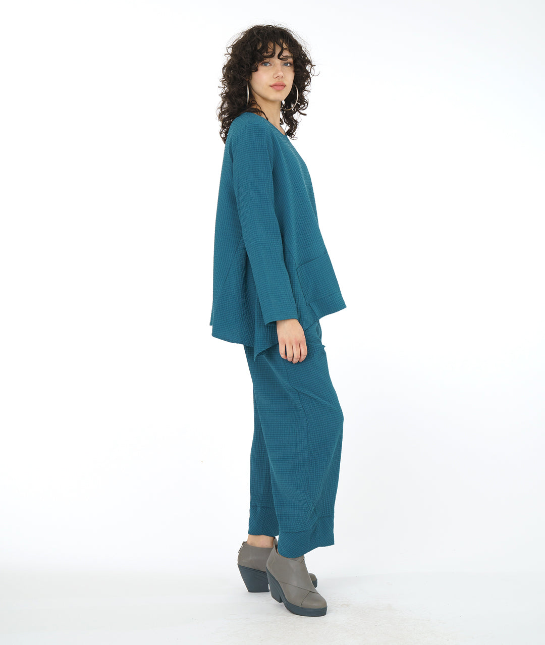 model in a teal flowy top with a matching textured pant with pockets, an elastic waistband, and a tapered cuff at the bottom hem