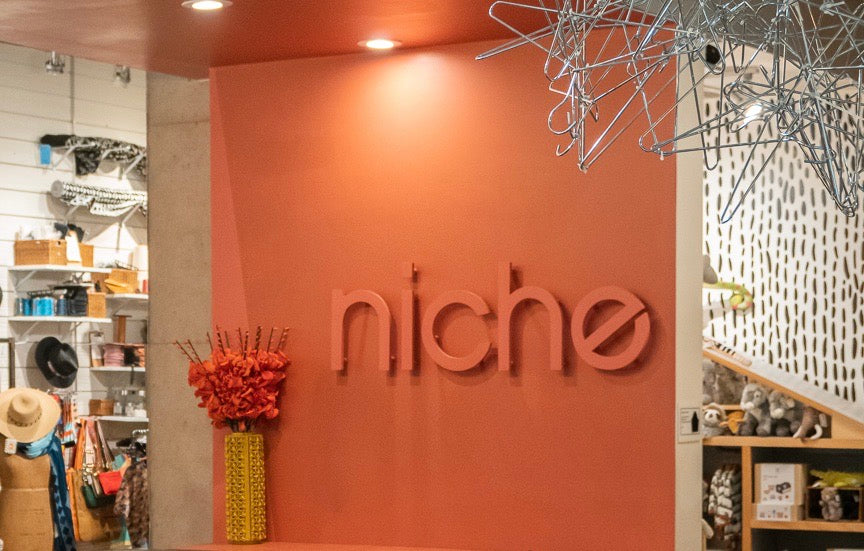 image shows a backdrop inside a boutique with the name "niche" on a coral wall