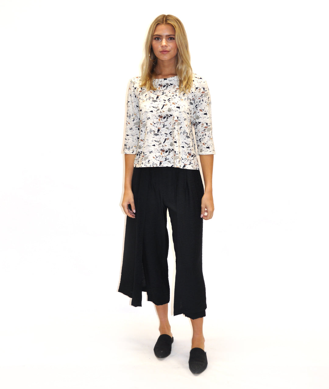 model in a black pant with a draped panel on either side, worn with a fitting terrazzo print top