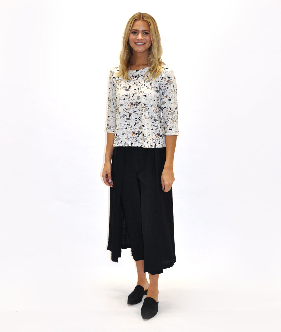 model in a black pant with a draped panel on either side, worn with a fitting terrazzo print top
