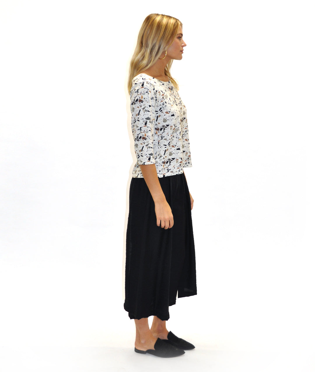 model in a black pant with a draped panel on either side, worn with a fitting terrazzo print top