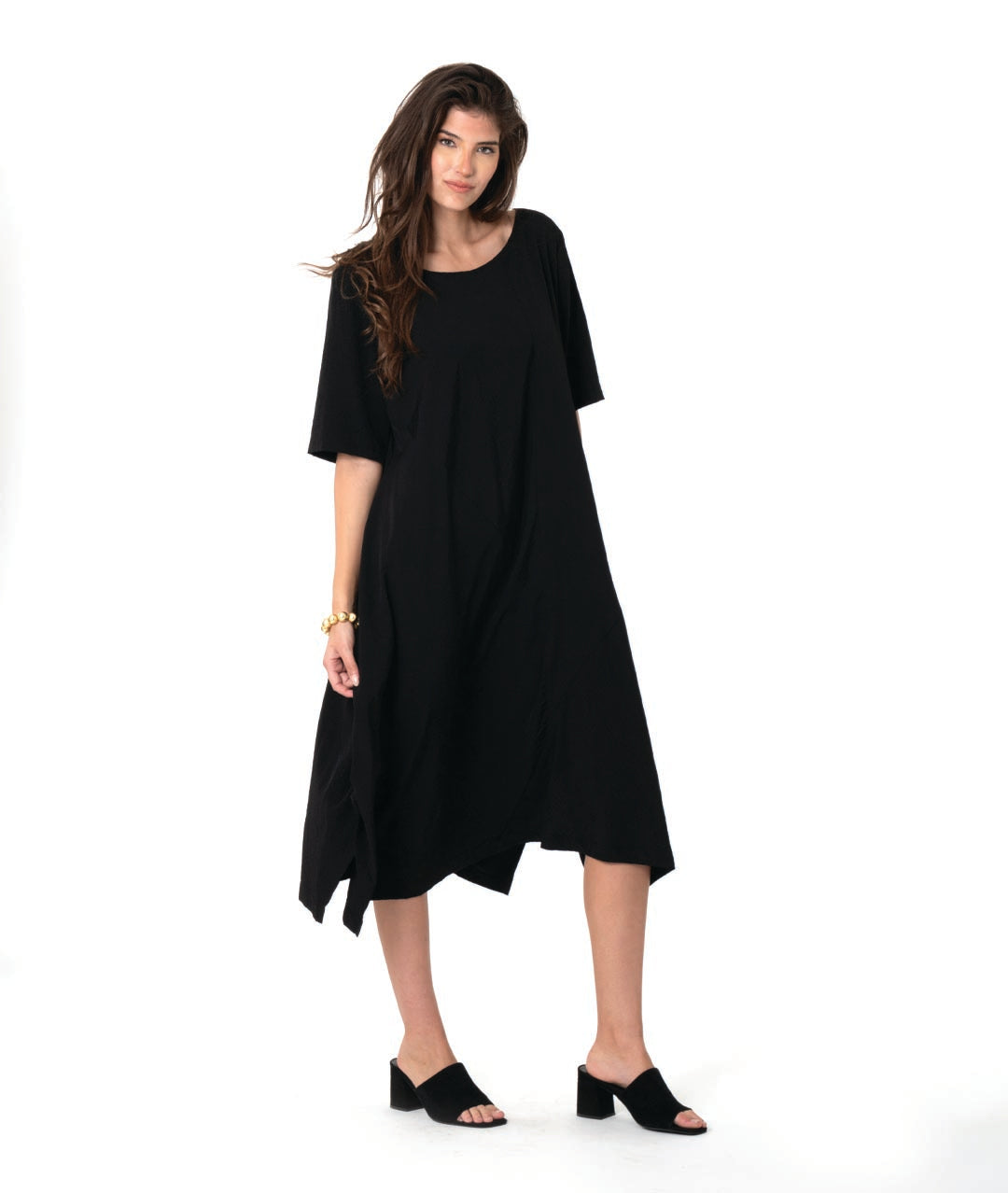 model in a pullover black dress with a slight grid texture. dress has a rounded neck, elbow length sleeves, and a flowy skirt with tucks and splits