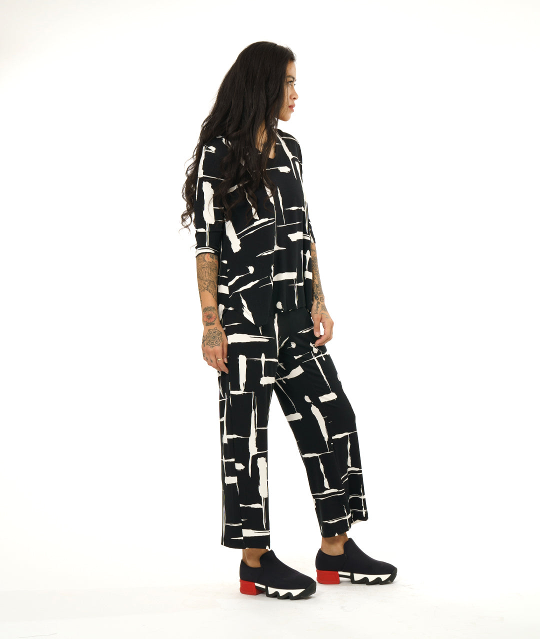 model in a straight leg black and white line print pant, with a matching v-neck top