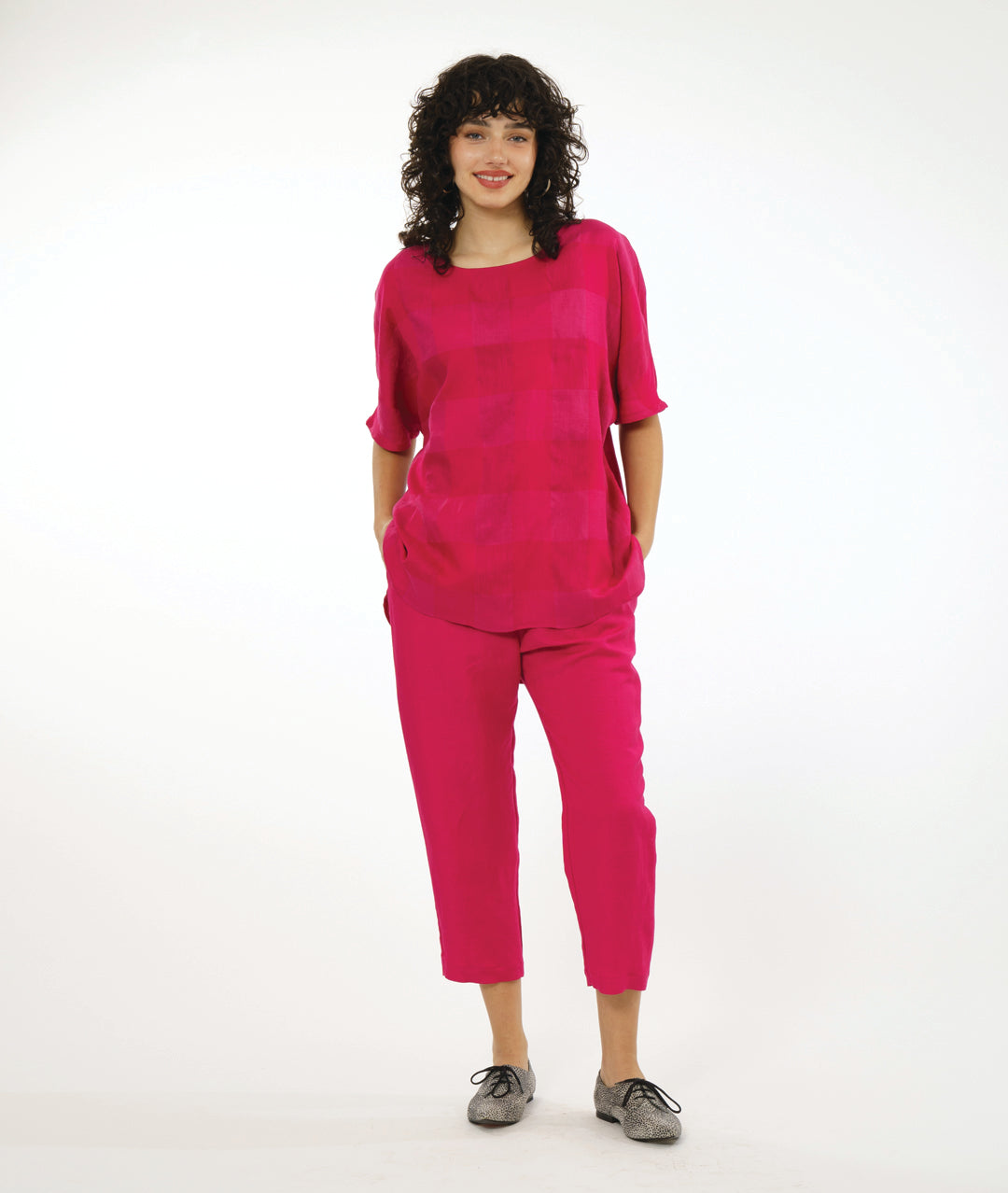 model in a hot pink cropped slim pant, with an oversized hot pink checkered pullover top