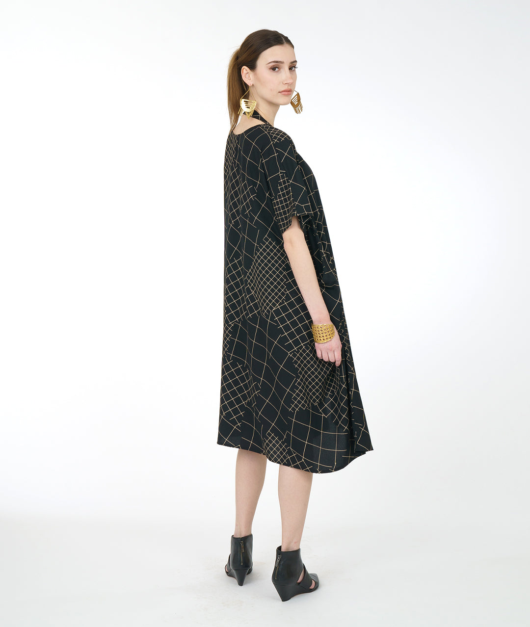 model in a black convertable tunic with an ivory grid pattern. tunic has a band from the hips that can be worn in different styles