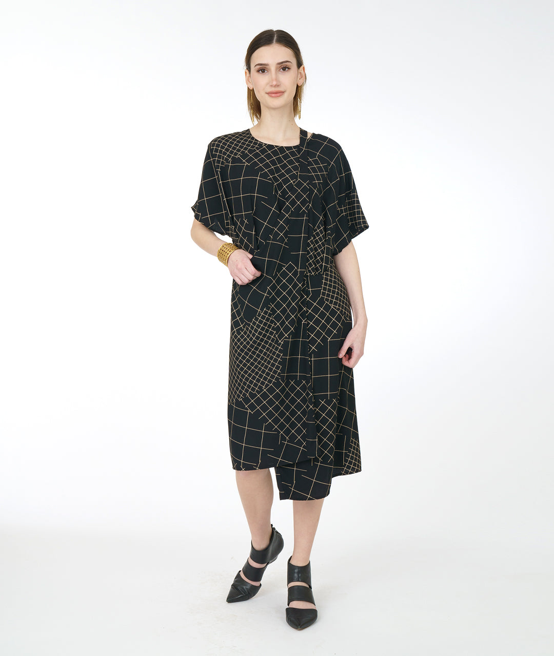 model in a black convertable tunic with an ivory grid pattern. tunic has a band from the hips that can be worn in different styles