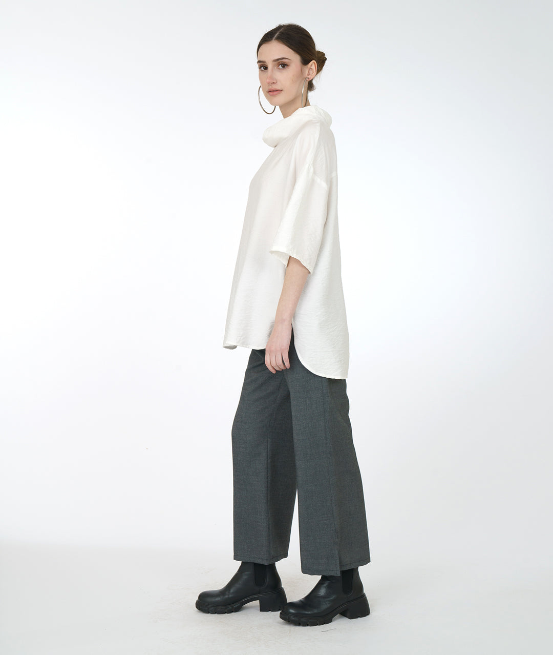 model in a grey wide leg pant, with a white cowl neck top with a drop shoulder
