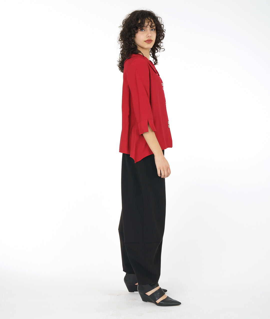 model in a wide leg black pant with a crimson red button down blouse with a 3/4 sleeve and a wide split cuff. blouse has a double button detail and flat collar