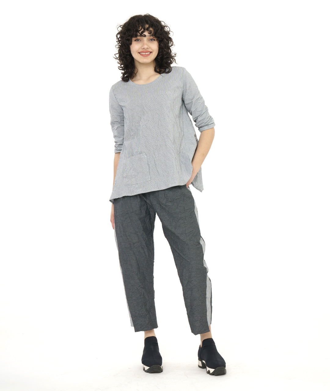 model in a grey and white pinstripe top with a crushed texture, with a matching pant in a black and grey stripe. Top has 3/4 sleeves, a single hip pocket and a full flowy body